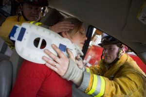 Injured woman trapped from car accident being rescued by firefighters.