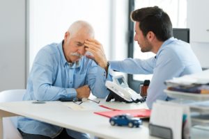 Worried older man consulting lawyer regarding car claims.