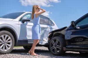 distraught woman looking at damage from a t-bone accident