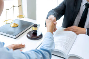 Lawyer with gavel and balance handshaking with client.