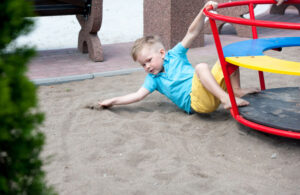 Little boy falls down on playground in the kindergarten.