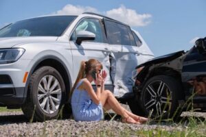 Crying lady driver calling her insurance to report car accident.